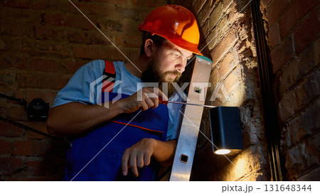 Technician checking wall light at night in low illumination Technician checking wall light at night in low illumination 131648344