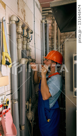 Technician checking heating pipes during maintenance work 131648474