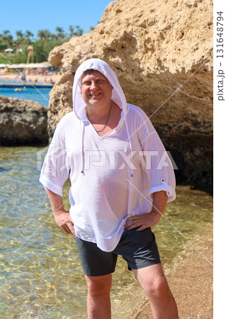 Tourist Man on Egyptian Beach Wearing a White Tunic and Hooded Cover to Beat the Heat, Enjoying the Sun and Sea in a Tropical Paradise 131648794