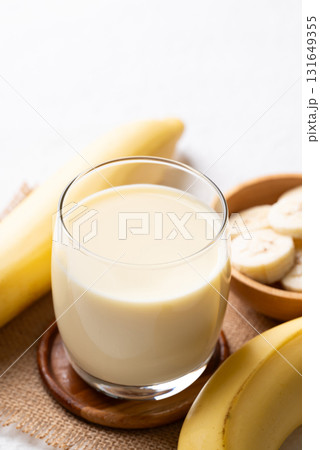 Banana milk in glass with sliced banana and fruit on white background 131649355