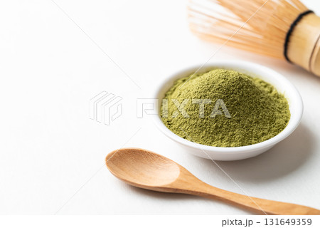 Matcha green tea powder in bowl with bamboo whisk and wooden spoon on white background Matcha green tea powder in bowl with bamboo whisk and wooden spoon on white background 131649359