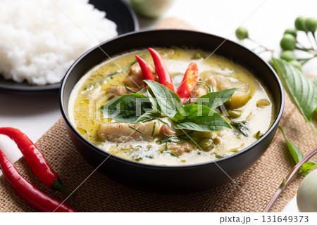Thai green curry chicken in black bowl with rice and ingredients Thai green curry chicken in black bowl with rice and ingredients 131649373