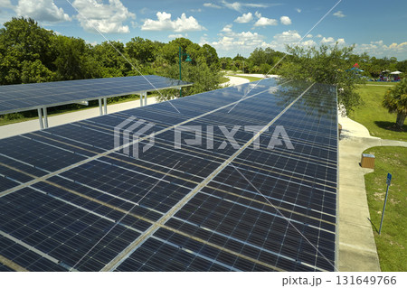 Aerial view of solar panels installed as shade roof over parking lot for parked cars for effective generation of clean electricity. Photovoltaic technology integrated in urban infrastructure Aerial view of solar panels installed as shade roof over parking lot for parked cars for effective generation of clean electricity. Photovoltaic technology integrated in urban infrastructure 131649766