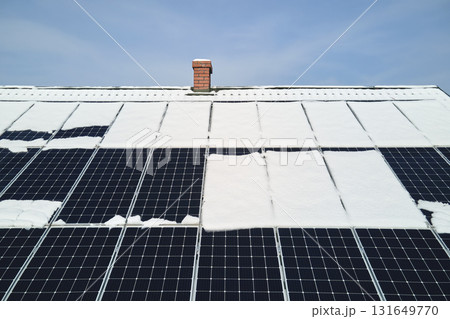 Aerial view of snow melting from covered solar photovoltaic panels installed on house rooftop for producing clean electrical energy. Low effectivity of renewable electricity in nothern region winter 131649770