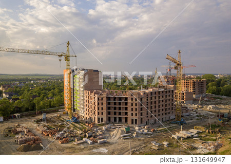 Aerial view of building site. Apartment or office building under construction. Tower cranes on suburb landscape and blue sky copy space background. 131649947