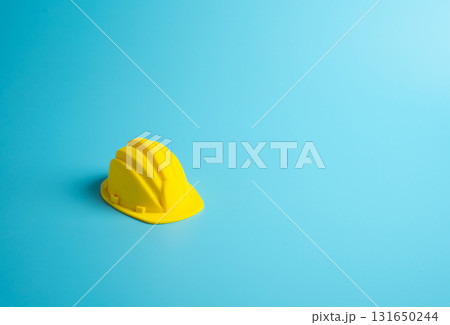 A yellow construction hardhat on a blue background. Construction, design, and project development. Repairs renovations. Concept of engineering, industrial safety, professional work. Labor protection 131650244