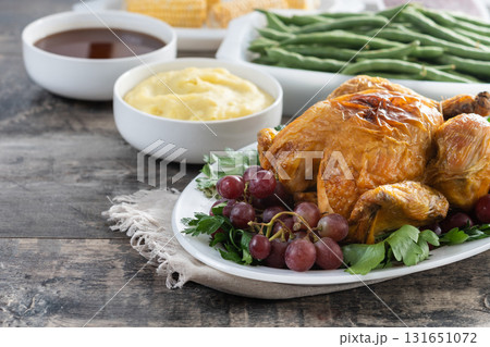 Thanksgiving dinner on rustic wooden table with turkey,mashed potatoes,ears of corn and green bean casserole	 131651072