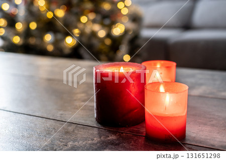 Red Christmas candles with holiday lights and christmas tree in background Red Christmas candles with holiday lights and christmas tree in background 131651298