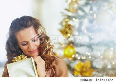 Woman Embracing a Golden Christmas Present with Closed Eyes Woman Embracing a Golden Christmas Present with Closed Eyes 131651422