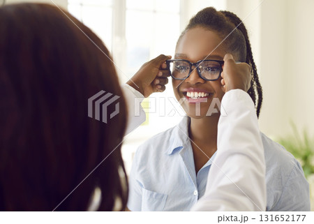 Happy African American female patient trying on glasses as recommended by ophthalmologist. Happy African American female patient trying on glasses as recommended by ophthalmologist. 131652177
