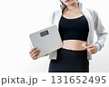 体重計を持ちお腹をつまむ女性　体を鍛えてるかっこいい女性　ダイエット　筋トレ女子　白バック 131652495