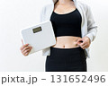 体重計を持ちお腹をつまむ女性　体を鍛えてるかっこいい女性　ダイエット　筋トレ女子　白バック 131652496