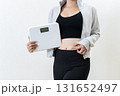 体重計を持ちお腹をつまむ女性　体を鍛えてるかっこいい女性　ダイエット　筋トレ女子　白バック 131652497
