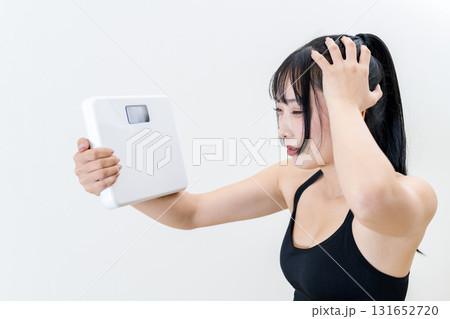 体重計を持ち頭を抱える女性　体を鍛えてるかっこいい女性　ダイエット　白バック　 131652720