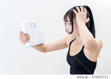 体重計を持ち頭を抱える女性 体を鍛えてるかっこいい女性 ダイエット 白バック 体重計を持ち頭を抱える女性 体を鍛えてるかっこいい女性 ダイエット 白バック 131652721
