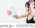 体重計を持ち頭を抱える女性　体を鍛えてるかっこいい女性　ダイエット　白バック　トリミングアップ 131652722