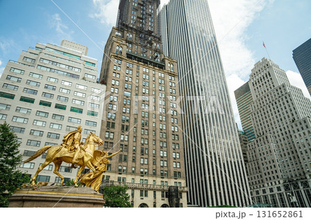 A striking view of the gilded William Tecumseh Sherman statue at Grand Army Plaza in New York City. Tall skyscrapers rise behind the monument under a bright summer sky, blending history and modern A striking view of the gilded William Tecumseh Sherman statue at Grand Army Plaza in New York City. Tall skyscrapers rise behind the monument under a bright summer sky, blending history and modern 131652861