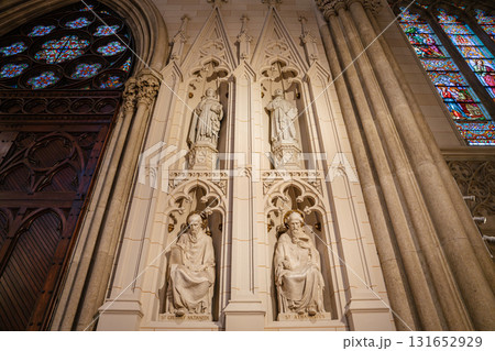 The image displays detailed stone statues of saints, including St. Gregory Nazianzen and St. Athanasius, inside St. Patrick's Cathedral in New York City. Surrounding Gothic architecture includes 131652929