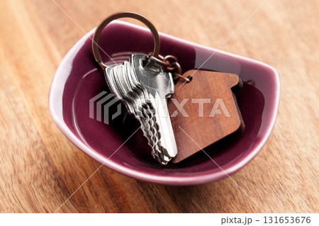 Set of hotel room keys with house keychain in ceramic bowl on wooden table 131653676