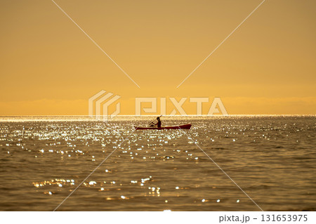 Kayaking, sunset, ocean, person paddling red kayak on sparkling water during golden hour with tranquil copy space Kayaking, sunset, ocean, person paddling red kayak on sparkling water during golden hour with tranquil copy space 131653975