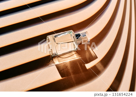 Is the perfume spray bottle lying on a beige background with shadow stripes. Is the perfume spray bottle lying on a beige background with shadow stripes. 131654224