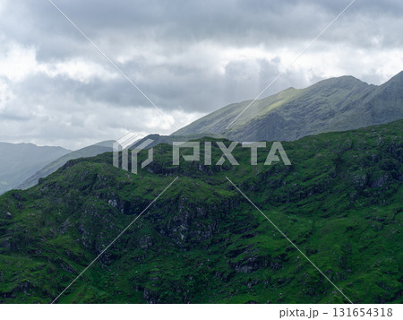 Rolling green hills meet a dramatic mountain range. Breathtaking vista perfect for backgrounds. 131654318