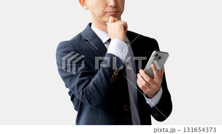 スマートフォンを見て考える男性ビジネスマン スマートフォンを見て考える男性ビジネスマン 131654373