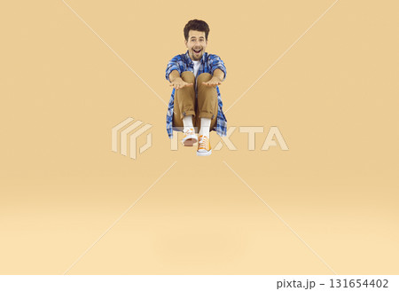 Happy young man having fun, jumping up on a trampoline and flying high in the air 131654402