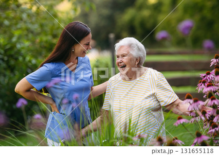 Home nurse spending time with elderly lady patient in garden. Home nurse spending time with elderly lady patient in garden. 131655118