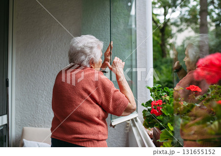Elderly woman closing window in apartment. Elderly woman closing window in apartment. 131655152
