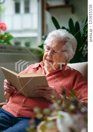 Senior lady sitting at balcony, reading book. Senior lady sitting at balcony, reading book. 131655156