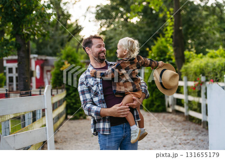 Farmer father holding little son in arms. 131655179
