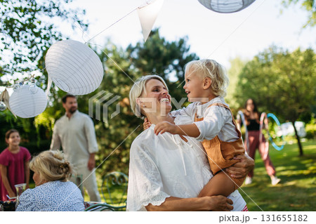 Candid shot of mom with toddler boy during family garden party. 131655182