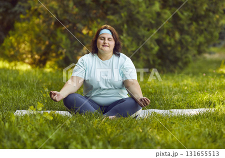 Calm young overweight woman doing meditation after outdoors exercise in city park. Calm young overweight woman doing meditation after outdoors exercise in city park. 131655513
