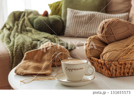 Cozy Living Room with Yarn, Pumpkins, Pillows and Cup of Cappuccino on White Table 131655573