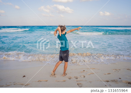 Teenage boy running on the sandy beach and playfully throwing stones into the ocean, enjoying freedom, energy and joy. Summer vacation, youthful fun, and carefree childhood concept 131655964