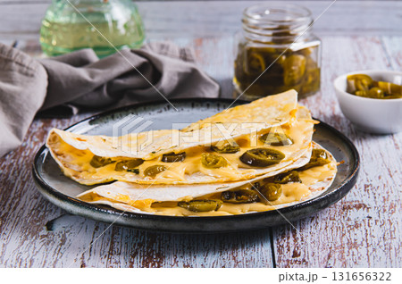 Spicy quesadilla with cheese and jalapeno pepper on a plate on the table 131656322