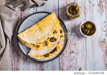 Spicy quesadilla with cheese and jalapeno pepper on a plate on the table top view 131656326