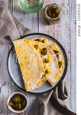 Cheese and jalapeno mexican quesadillas on a plate on the table top and vertical view 131656328