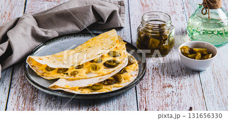 Spicy quesadilla with cheese and jalapeno pepper on a plate on the table web banner Spicy quesadilla with cheese and jalapeno pepper on a plate on the table web banner 131656330