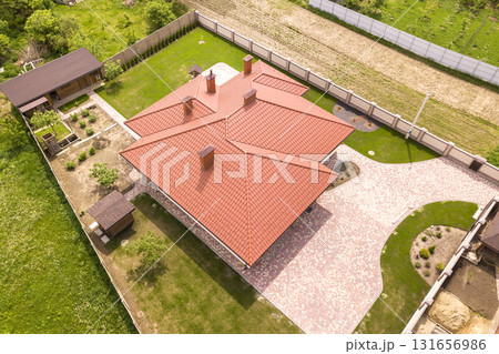 Aerial top view of new residential house cottage with shingle roof on fenced big yard on sunny day. 131656986