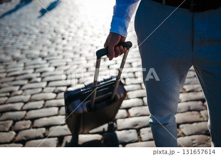Businessman pulling suitcase on cobblestone street. Businessman pulling suitcase on cobblestone street. 131657614