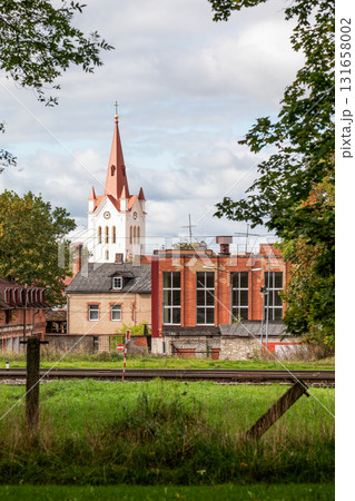 Historic church tower with red spire rising above old residential and industrial brick buildings  131658002