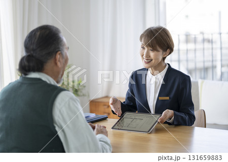シニア男性にタブレットで資料を見せながら話をするビジネスウーマン 131659883