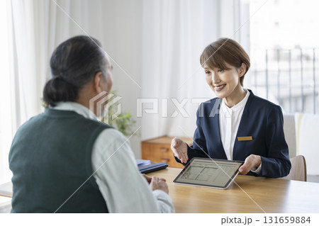 シニア男性にタブレットで資料を見せながら話をするビジネスウーマン 131659884