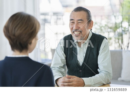 ビジネスウーマンと向き合って話をする70代の男性 131659889