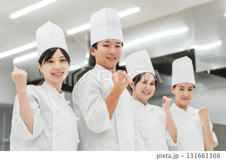 厨房・キッチンに立つコックコート姿の調理師・シェフ・コックの男女（ガッツポーズ,やる気）） 131661308
