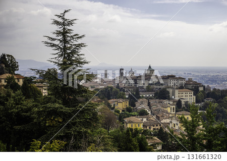 Panoramic view of Bergamo Citta Alta with historic towers and domes surrounded by greenery on a cloudy day Panoramic view of Bergamo Citta Alta with historic towers and domes surrounded by greenery on a cloudy day 131661320