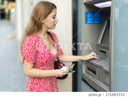 Young woman withdrawing a day from an atm Young woman withdrawing a day from an atm 131661552