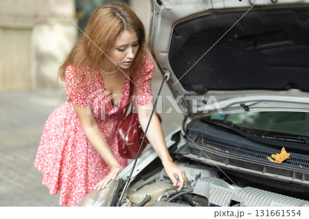 Woman looking under the hood of the car 131661554